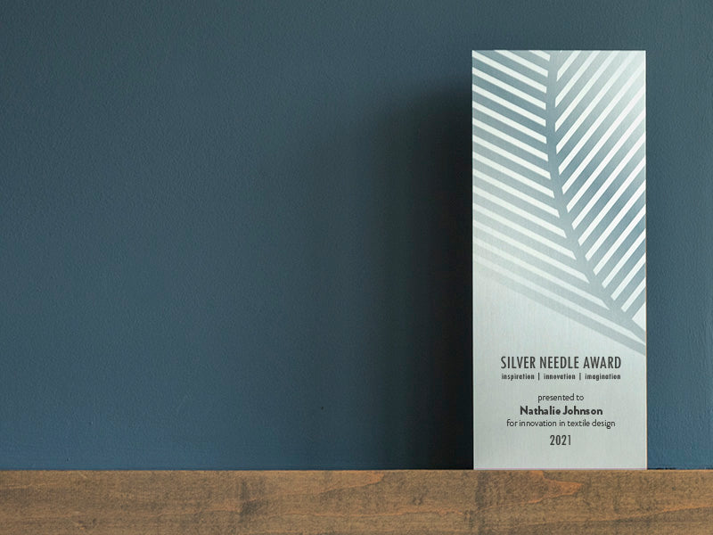 Modern FSC-Recycled award with leaf-inspired design, displayed on a bookshelf beside fashion books—crafted in the USA from sustainable materials.