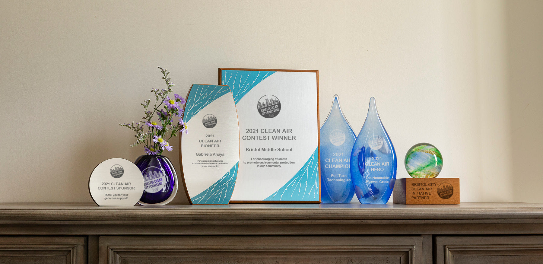 A collection of eco-friendly Clean Air Awards, including artisan glass, bamboo, and recycled metal, honoring community impact and leadership.