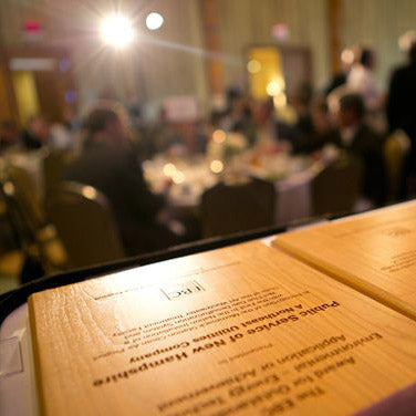 A stack of wooden plaques waits backstage at a formal recognition event.