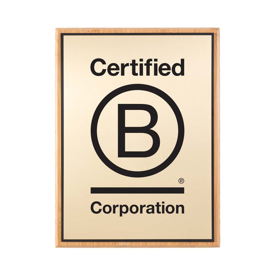 Brushed gold Certified B Corporation plaque with bold logo, mounted on a natural bamboo backer.